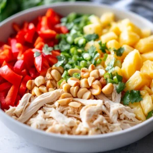 Tropical Hawaiian Chicken Salad is a delightful blend of flavors and textures, ideal for those looking for a refreshing, low-carb meal. This salad combines tender, shredded chicken with sweet, juicy pineapple, crunchy red bell peppers, and fresh green onions, all brought together with a creamy dressing made from plain Greek yogurt. The included fresh cilantro adds a burst of flavor, making this salad not only vibrant in appearance but also in taste. Perfect for summer picnics or light dinners, this dish is sure to transport your taste buds straight to the tropics.